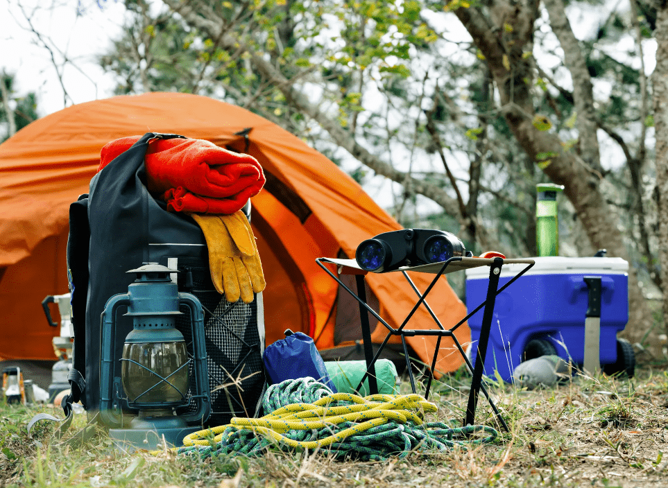 Hunting camp setup in the forest binoculars ropes backpack and blankets palced on the groound