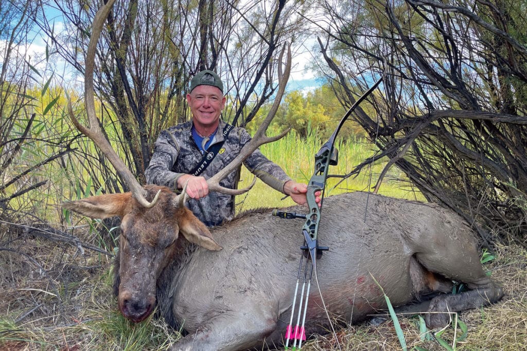 a man with his hunted elk with bow