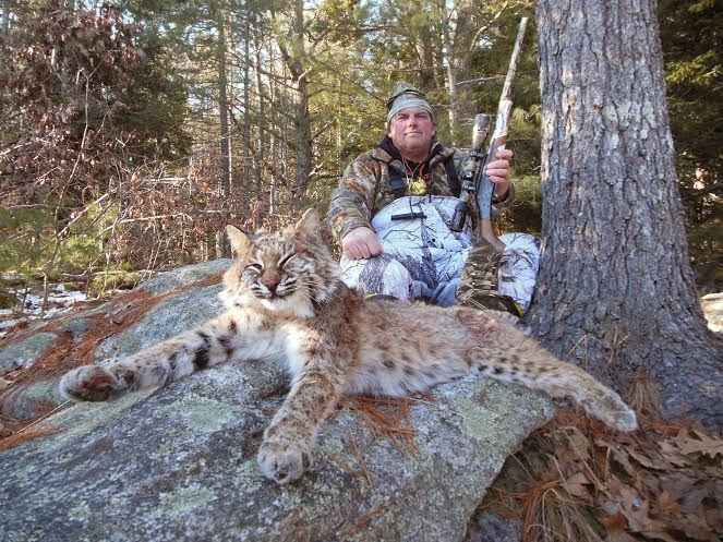 a hunter with his gun and bobcat