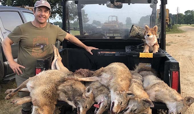 a man with numbers of hunted coyotes in his jeep