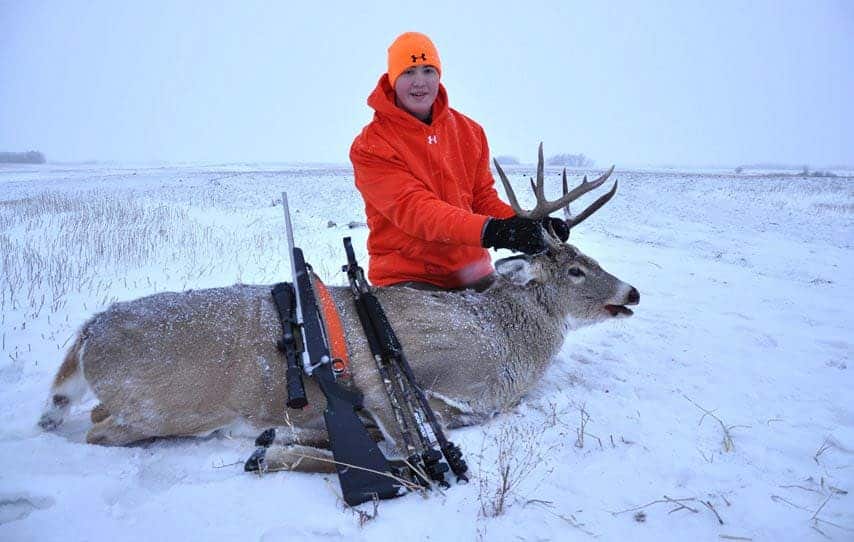 a hunter with a hunted deer in snowy weather