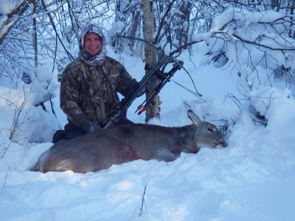 a hunter with hunted deer in snow