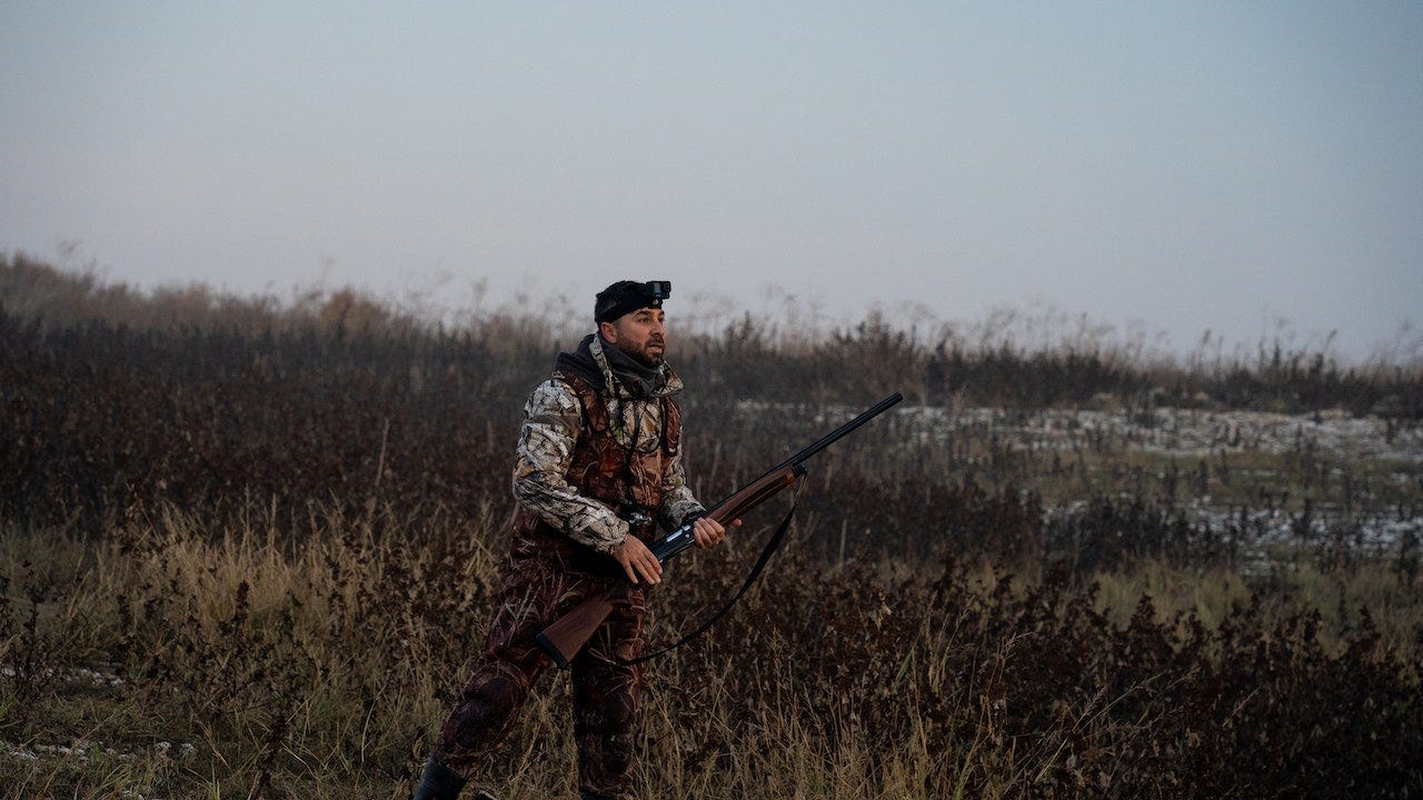 a man holding a riffle while hunting in a jungle