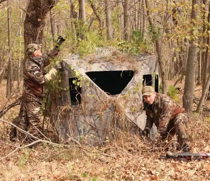 hunters setting the hunting ground blinds in woods