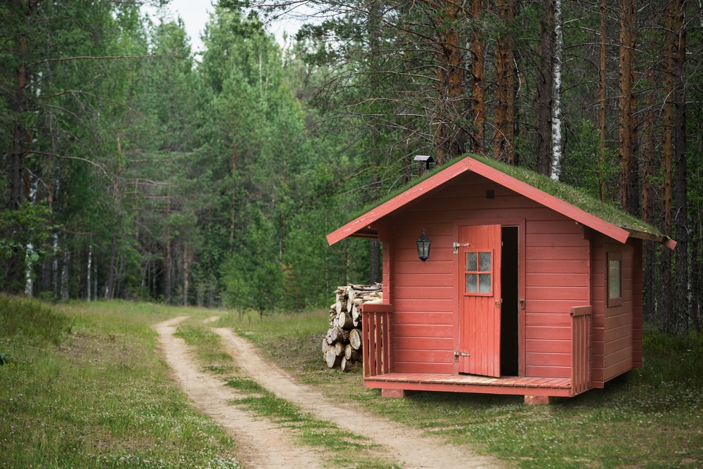 Red Wooden Hunting Lodge With Grass On The Roof Near